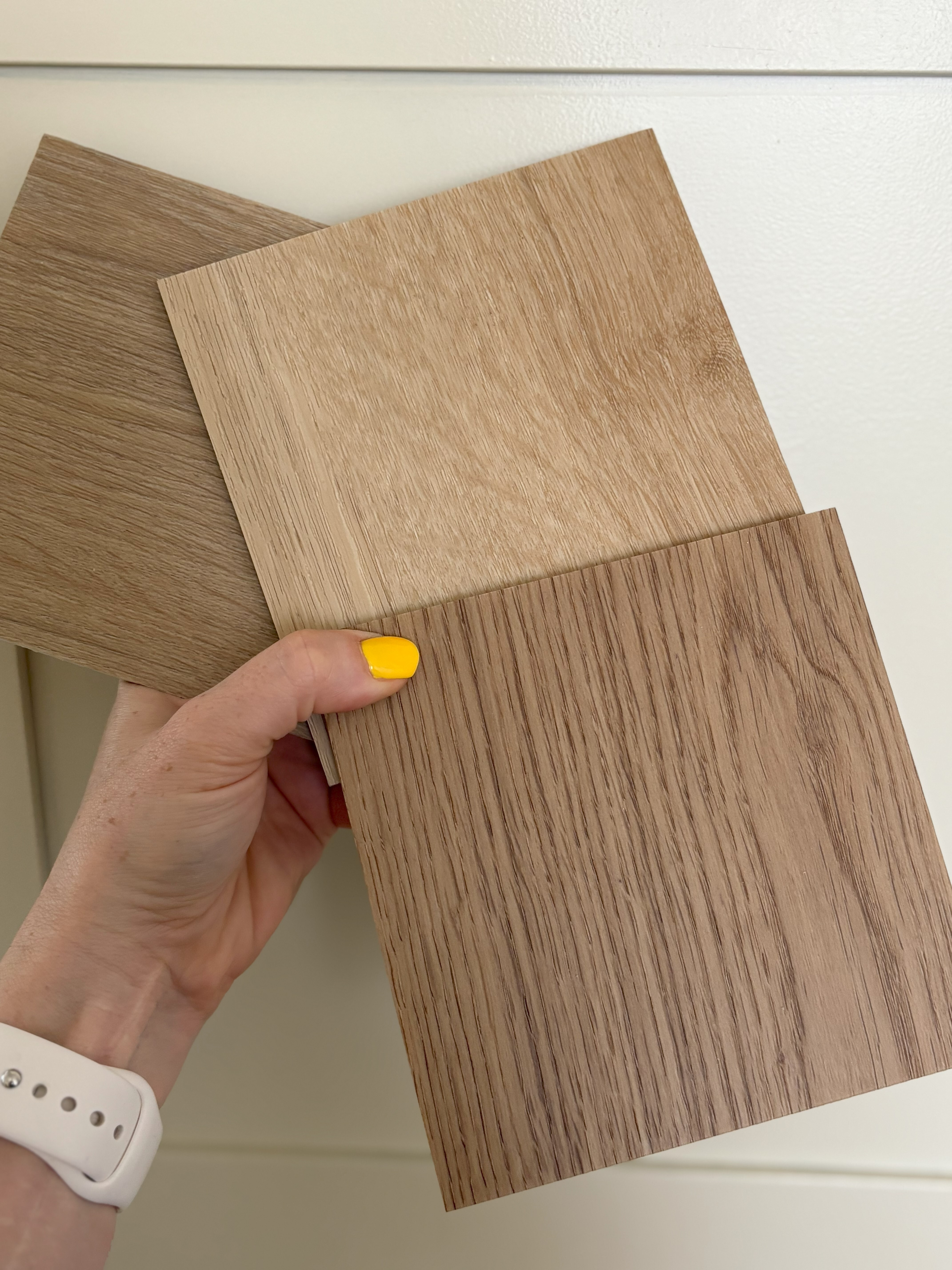 Różne wzory imitujące drewno paneli winylowych ręka kobieca z żółtymi paznokciami trzyma próbki podłóg winylowych imitujących drewno